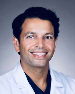 Sanjay Menon, MD, founder of Navika, in a white coat.